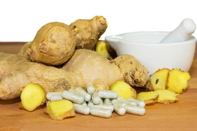 Ginger root accompanied by a motor and pestal with supplements capsules.